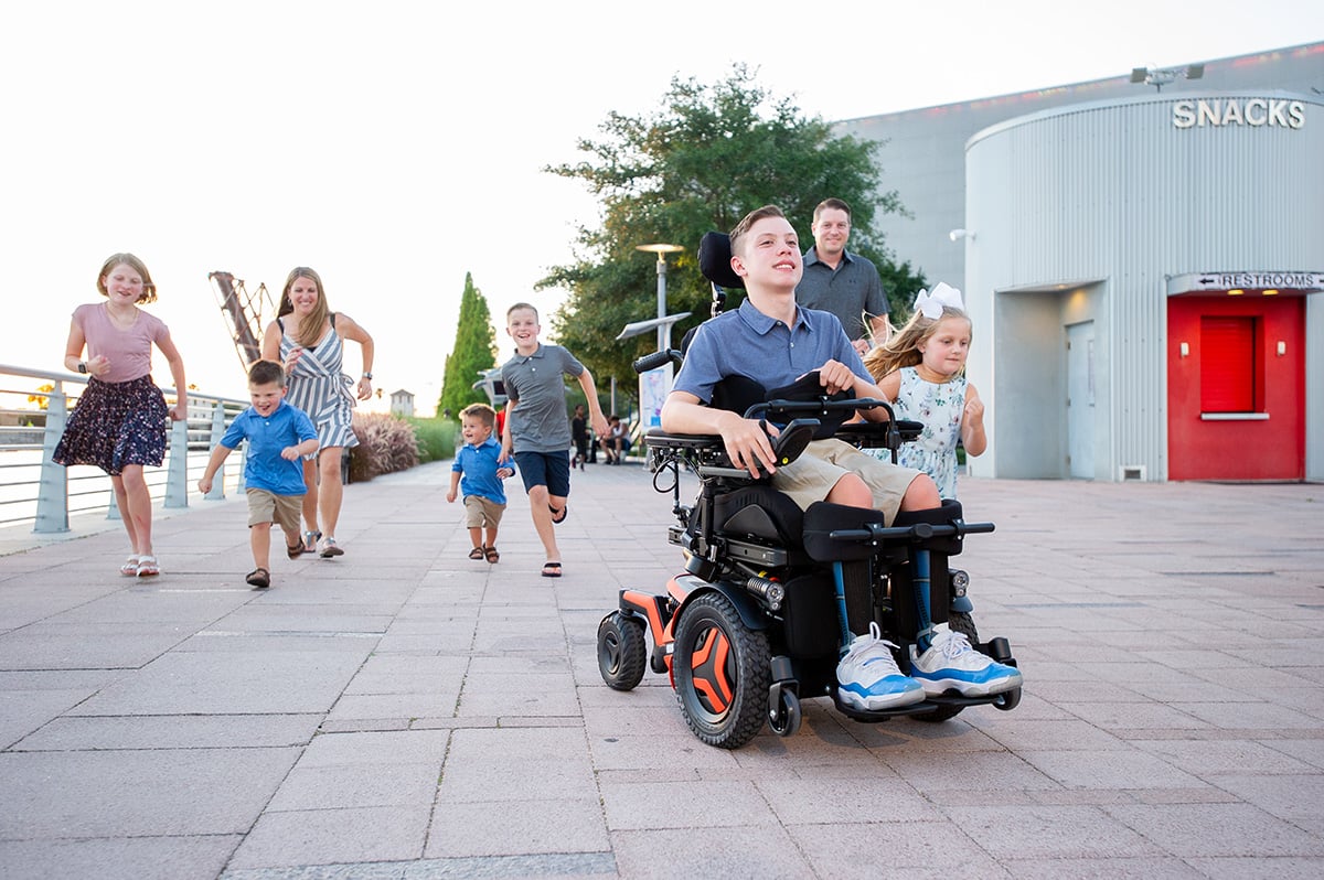 A boy driving wheelchair with family
